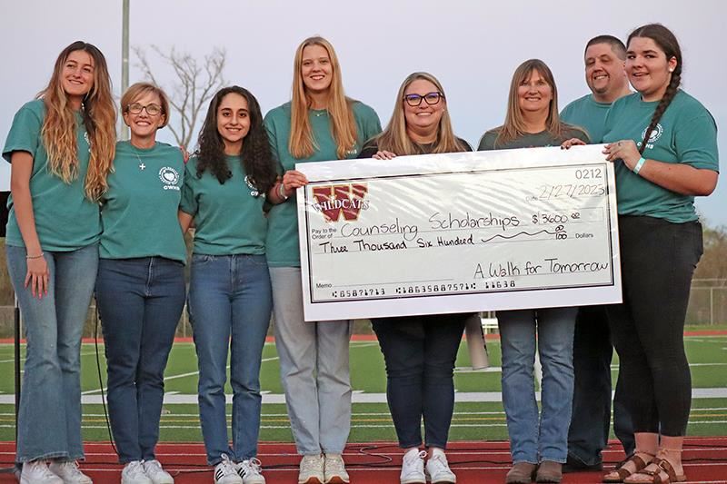 Members of the Cypress Woods High School Wildcat Mental Health Alliance (WMHA) present a check worth $3,600.